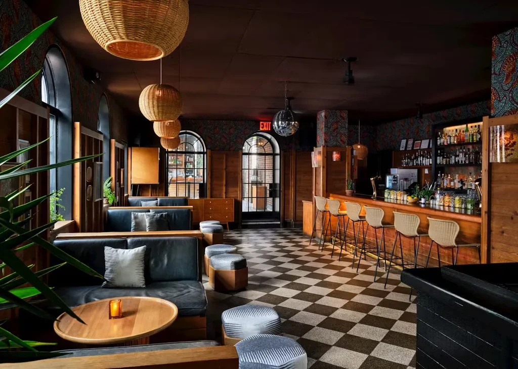 Stylish bar with leather seating, wooden bar, and checkerboard floor.