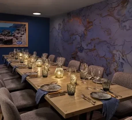 Long dining table set with plates, cutlery, and lanterns.