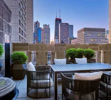 Rooftop patio with dark tables and chairs overlooking a city skyline.