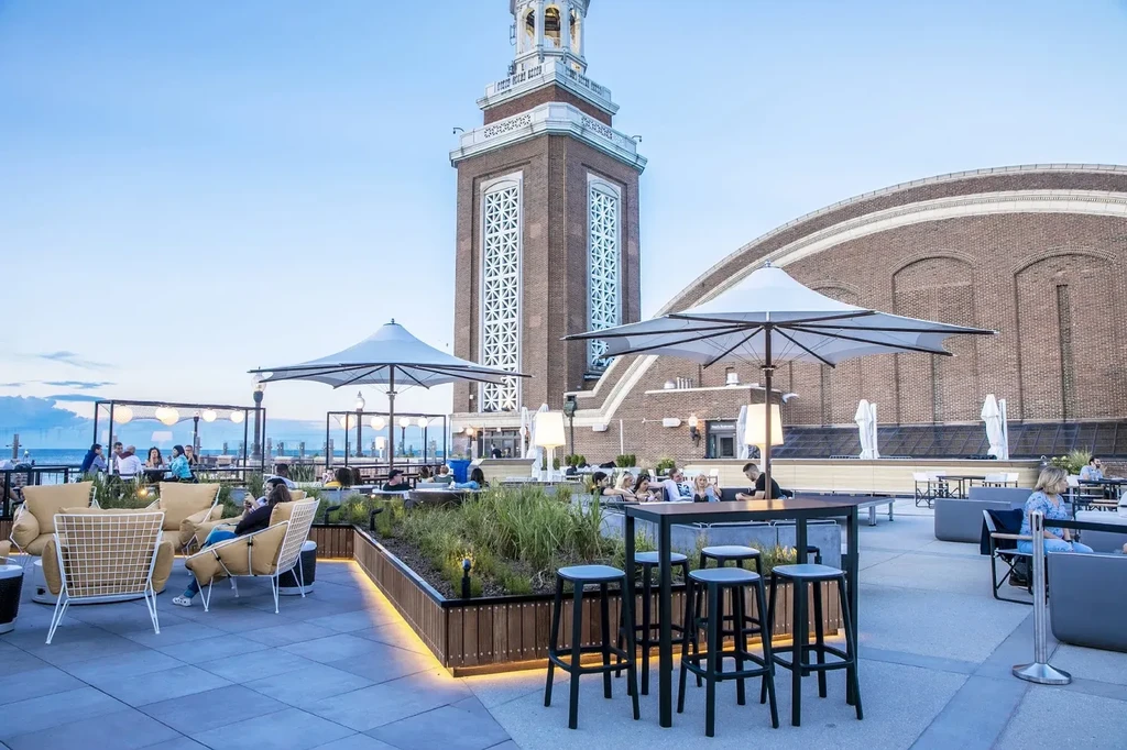 Rooftop restaurant with modern seating, umbrellas, and a brick tower.