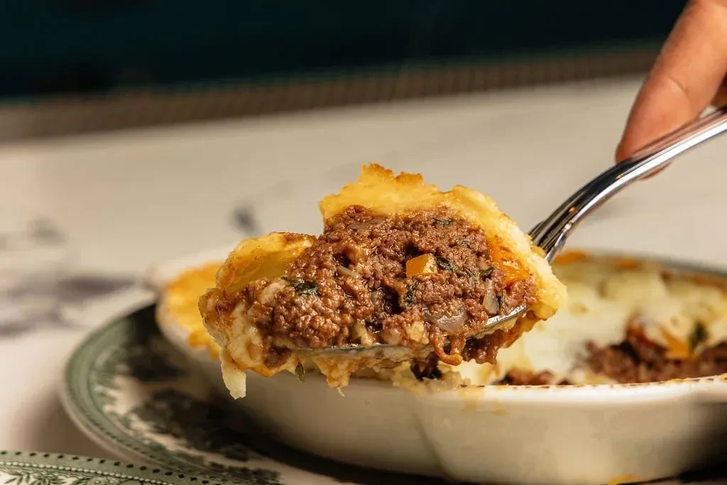 Spoonful of shepherd's pie with mashed potato topping and meat filling.
