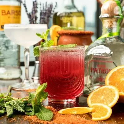 Still life of cocktails, spirits, and ingredients on a bar.