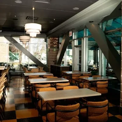Restaurant dining area with orange chairs and checkerboard floor.