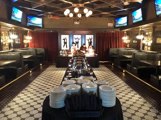 Restaurant buffet setup with chafing dishes, plates, and patterned floor.