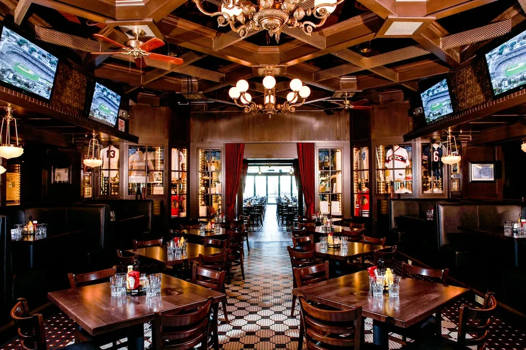 Upscale restaurant/sports bar with dark wood, sports memorabilia, and TV screens.