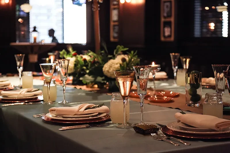 Elegantly set dining table with hydrangeas, candles, and copper charger plates.