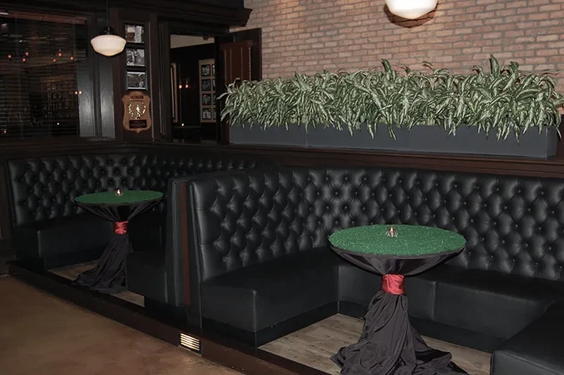 Restaurant interior with black leather booths and green glitter tables.