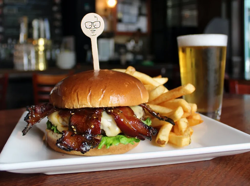 Burger, fries, and beer on a white plate in a restaurant.