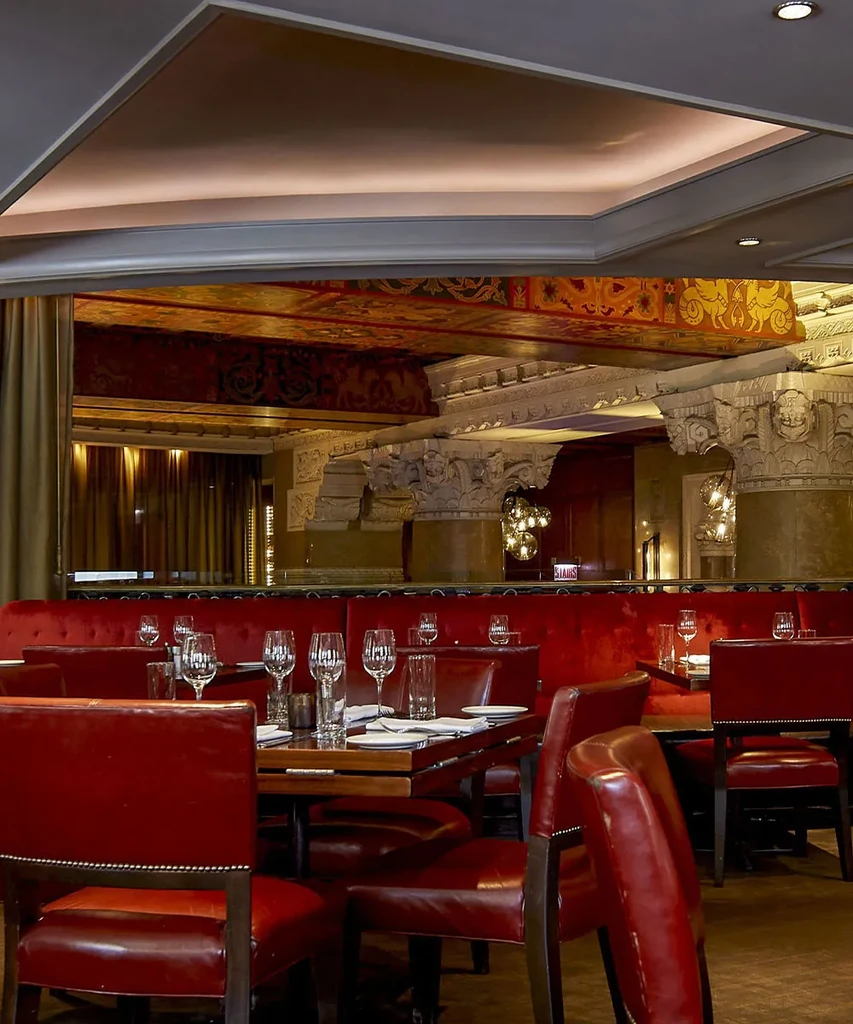 Elegant restaurant interior with red leather seating and ornate decor.