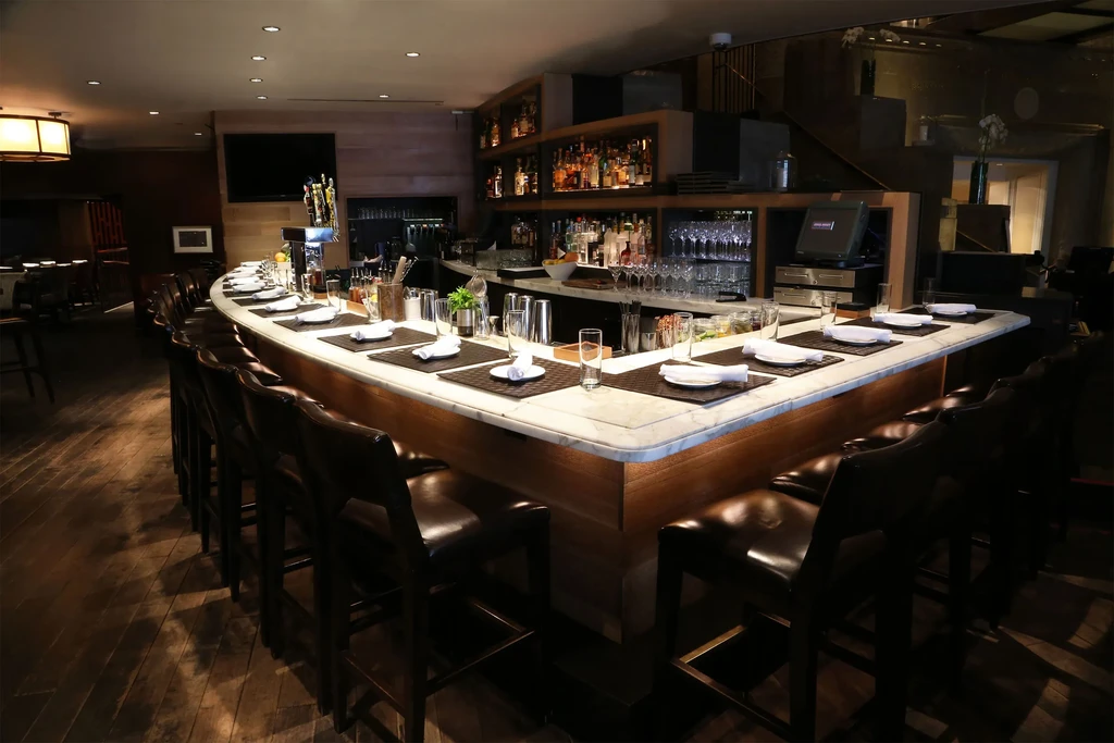 Sophisticated bar with marble counter, leather stools, and dining place settings.