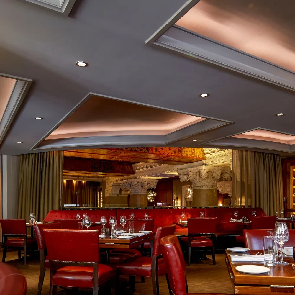 Dimly lit restaurant interior with red leather chairs and velvet booths.