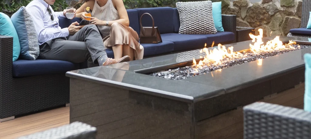 Outdoor patio with fire pit and two people on a sectional sofa.