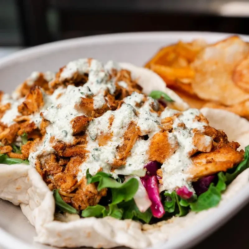Pita bread filled with meat, lettuce, cabbage, and white sauce.