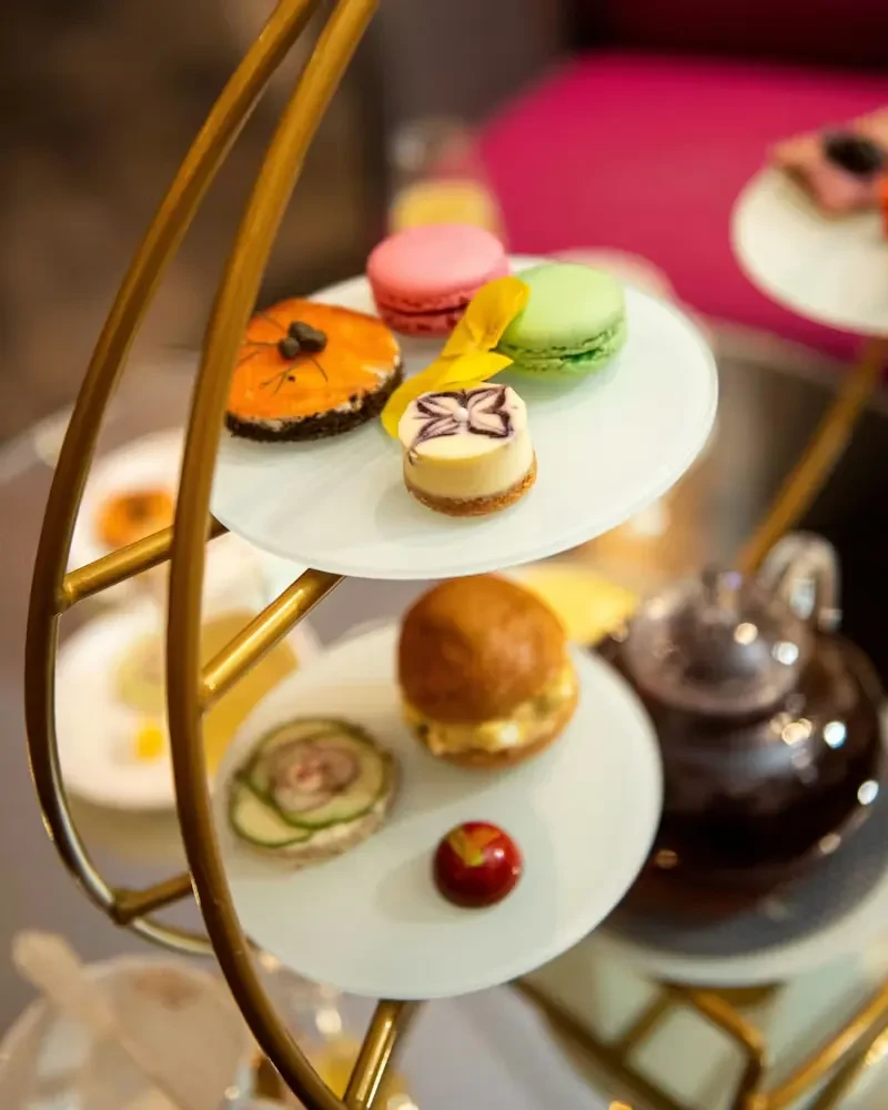 Two-tiered stand with macarons, pastries, a slider, and other mini desserts.