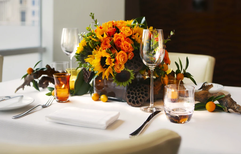Elegant dining table with floral centerpiece, kumquats, and votive candles.