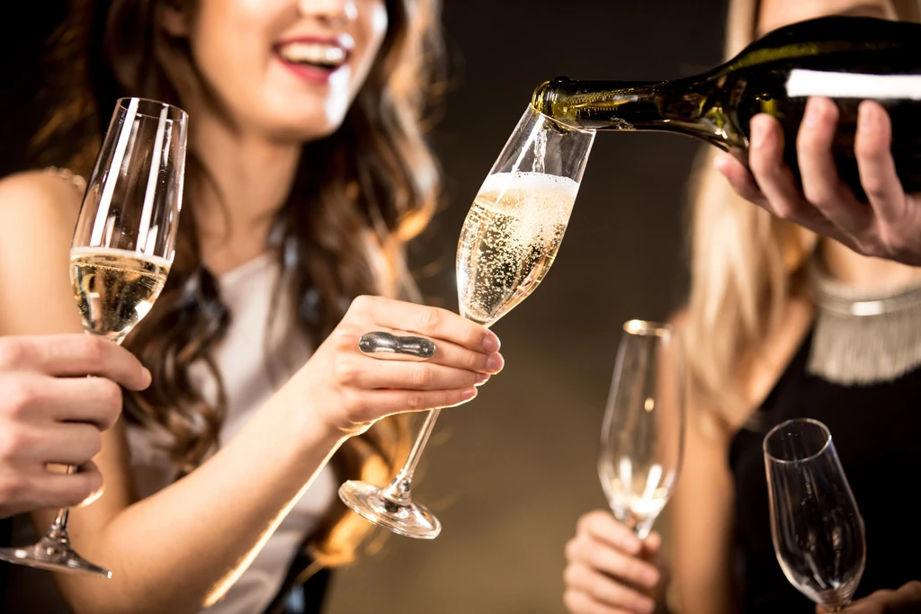 Champagne pours into a flute glass held by a woman.