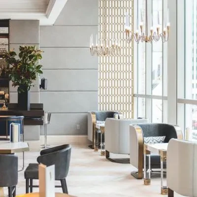Modern restaurant interior with plush seating, geometric patterns, and chandeliers.