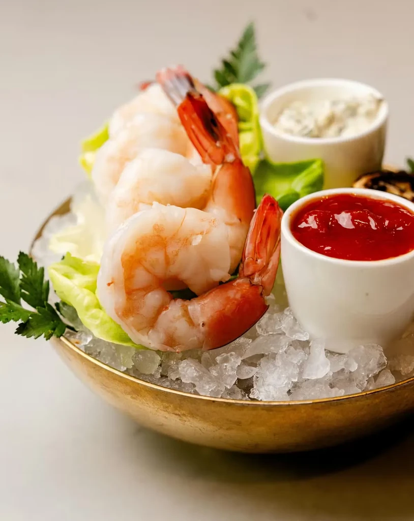Shrimp cocktail in a gold bowl with two sauces.