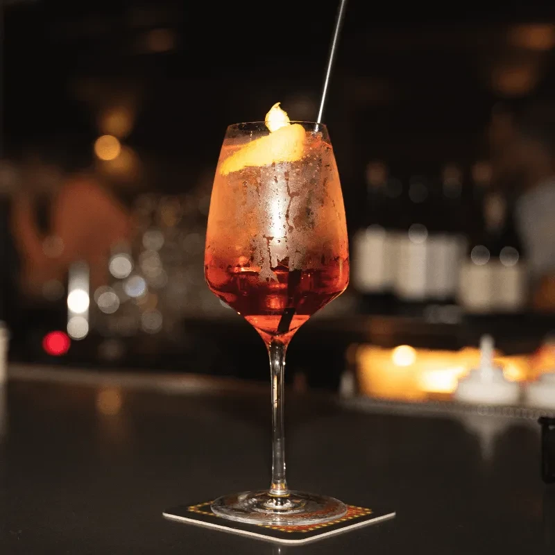 Chilled orange or red cocktail with citrus in a stemmed glass.