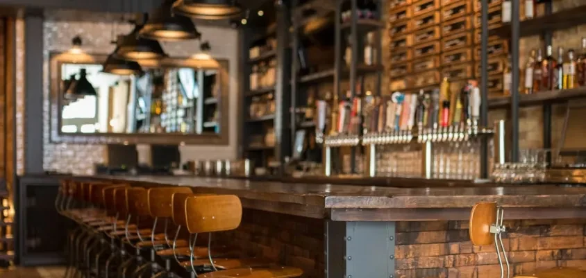Stylish bar interior with a long wooden counter and many stools.