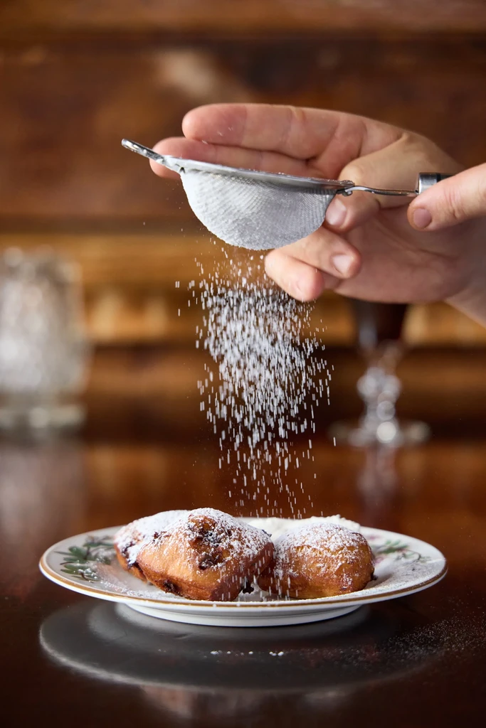 Fritters dusted with powdered sugar on a white plate.
