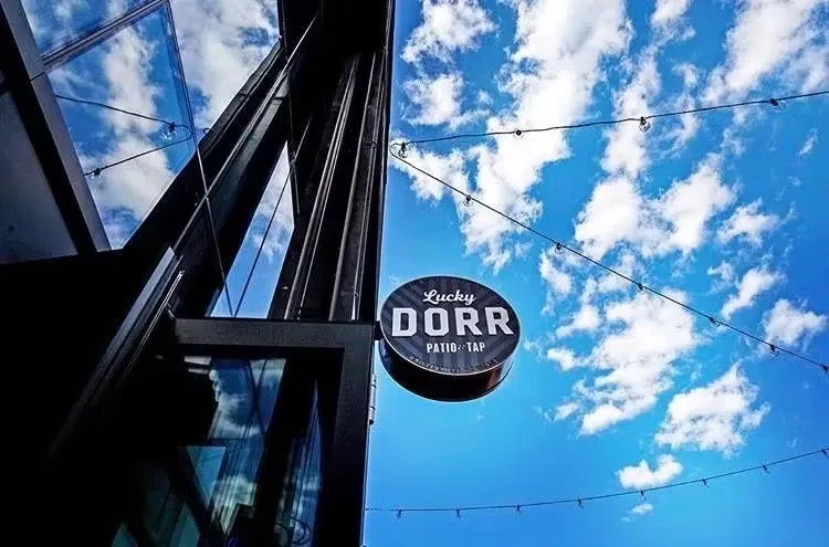 Lucky Dorr Patio + Tap sign against a blue sky.