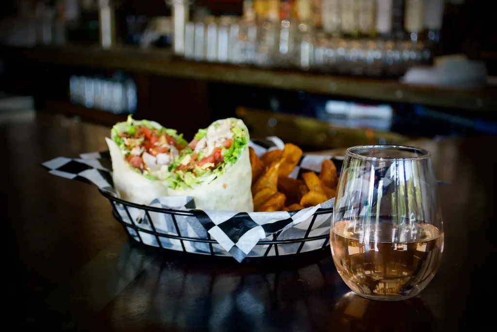Wrap and fries in a basket with a glass of rosé wine.