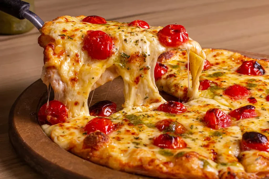 A slice of pizza with cheese and tomatoes being lifted.