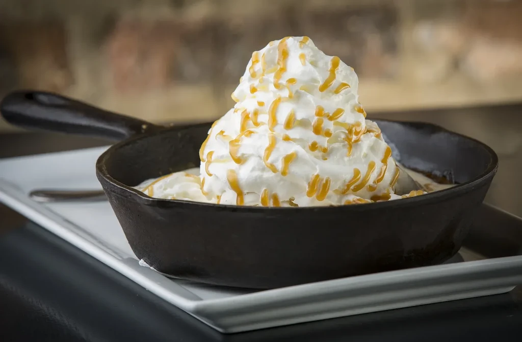 Dessert in cast-iron skillet, topped with whipped cream and caramel.