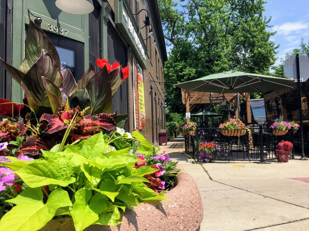 Exterior of a building with planters, patio, and green trees.