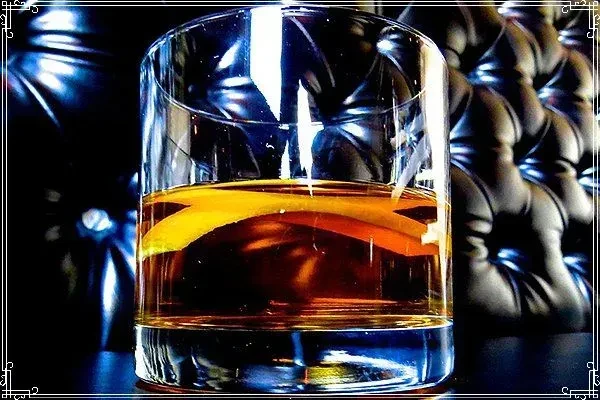 Amber drink with citrus peel in a clear glass.