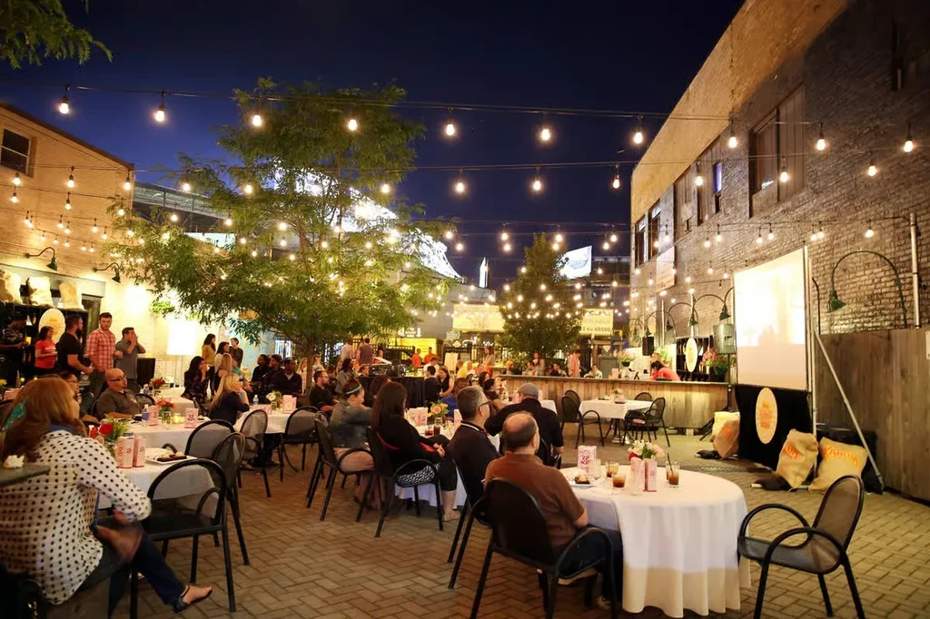 Evening patio event with tables, string lights, and a projection screen.
