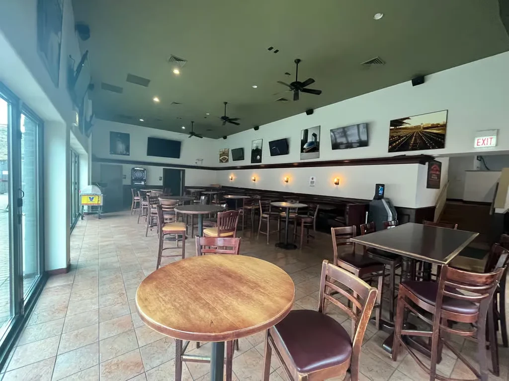 Casual restaurant interior with wooden tables, tiled floor, and arcade games.