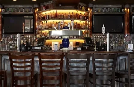 Interior view of a well-stocked bar with stools and televisions.