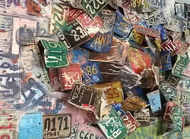 A wall covered with an overlapping collection of old, weathered license plates.