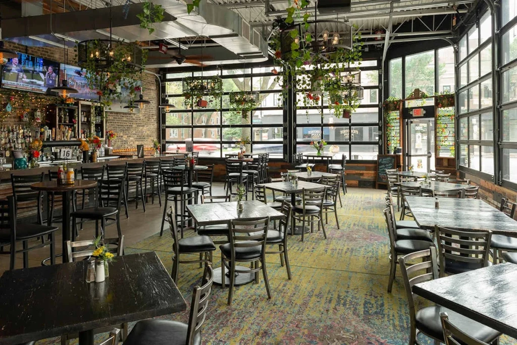 Interior of a modern-industrial restaurant with tables, chairs, and a bar.