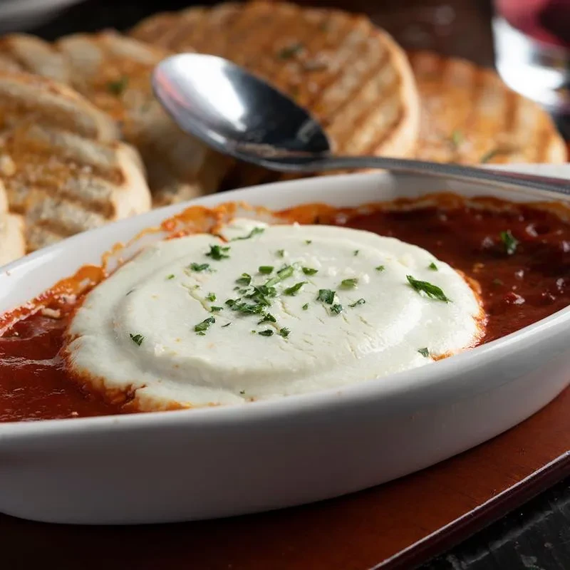 Tomato sauce and ricotta in a white baking dish.