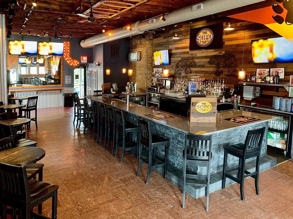 Restaurant bar with stone facade, wooden walls, and industrial lighting.