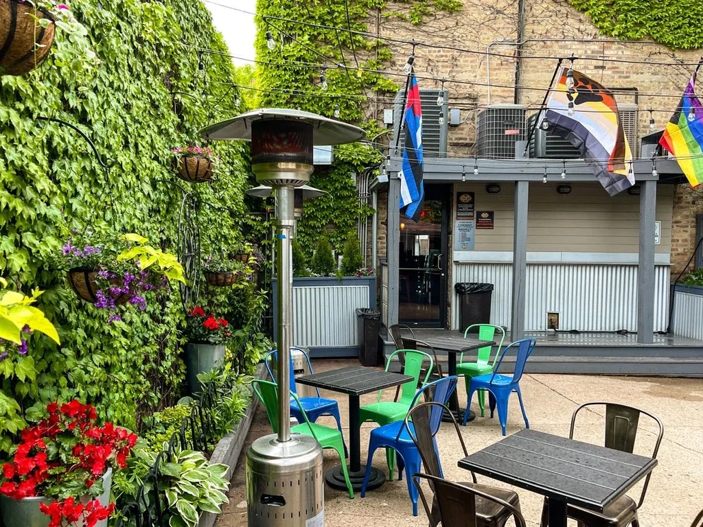Outdoor patio with tables, chairs, plants, and string lights.