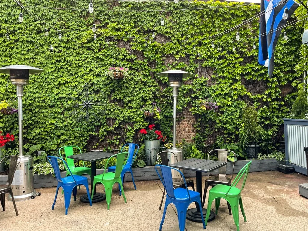 Outdoor patio with ivy wall, string lights, and heaters.