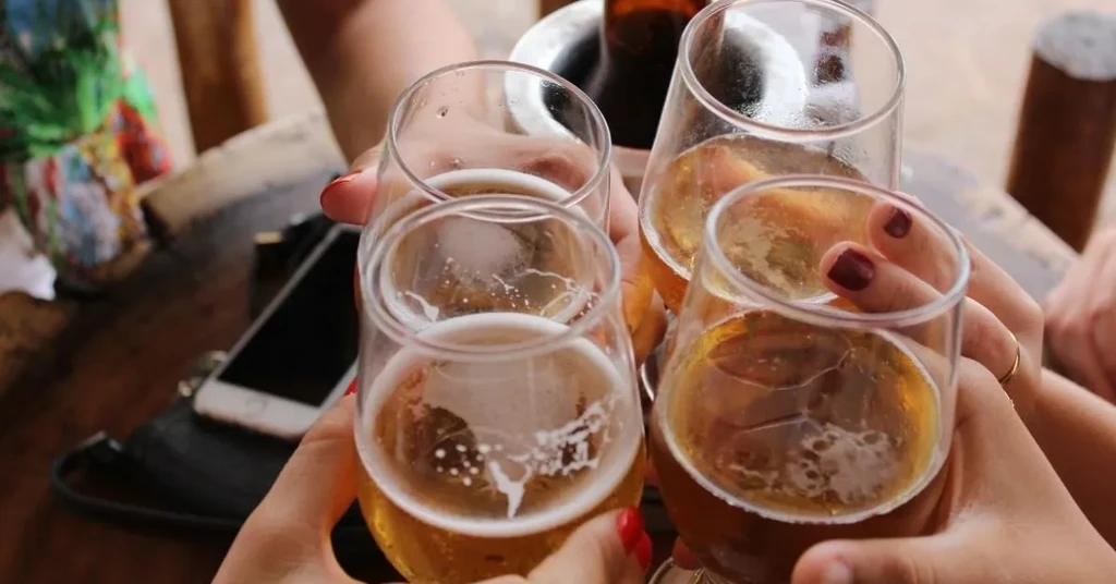 Four people toast with cold glasses of beer.