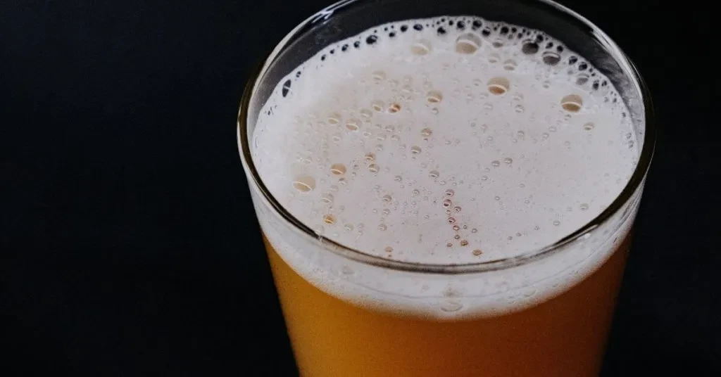 Close-up, top-down view of beer with foam in a glass.