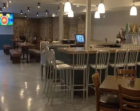 Interior of a bar or restaurant with wooden tables and a bar.