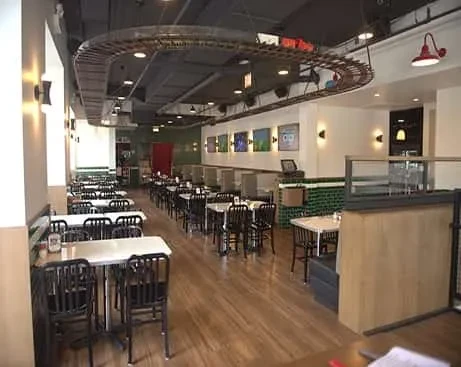 Empty restaurant dining room with suspended train tracks on the ceiling.