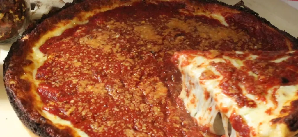 Deep-dish pizza, with a pulled slice showing stretchy cheese.
