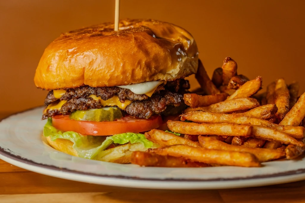Double cheeseburger with lettuce, tomato, pickles, and a side of fries.