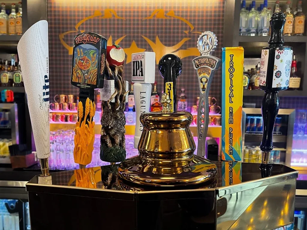 Close-up of a bar with eight distinct beer tap handles.