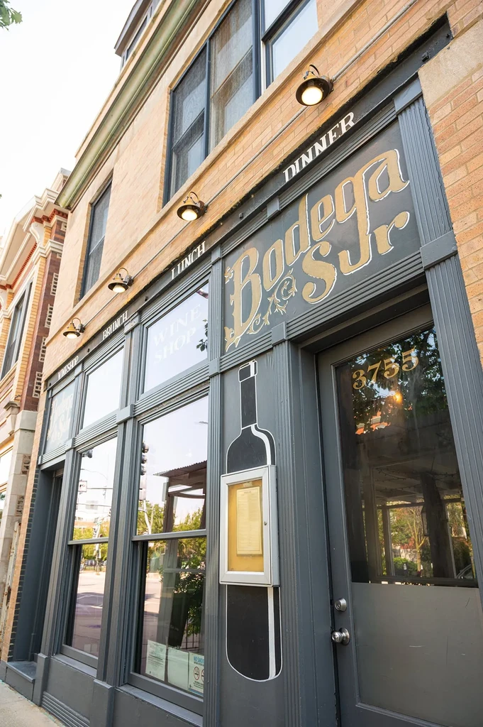 Storefront of Bodega S Jr. with gold lettering and a wine bottle design.