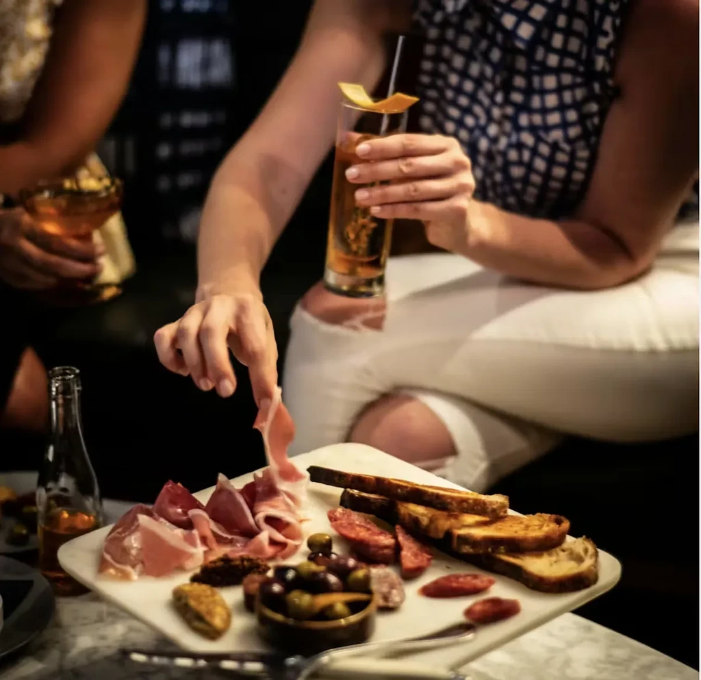 Close-up of a charcuterie board with a hand reaching for meat.