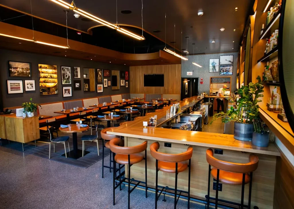 Modern restaurant interior with a long wooden bar and dining area.